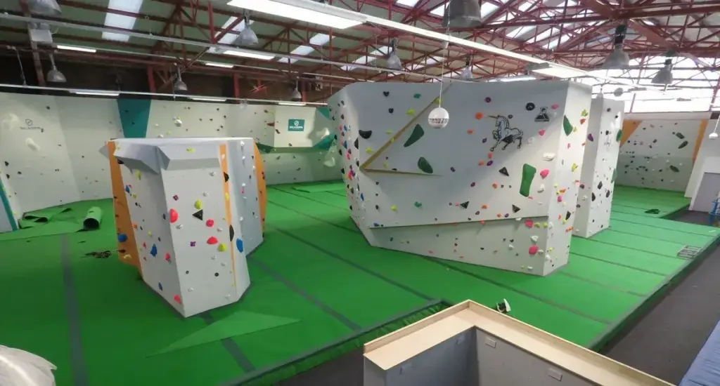 Interior of Climb Newcastle With Sections of Large Climbing Walls on a Green Carpet