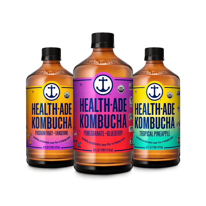 Three Bottles of the Brand Health-Ade Kombucha In Colours Ranging From Orange, Yellow, and Purple